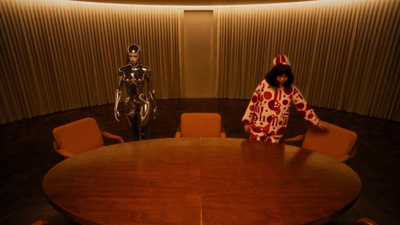 Still from the studio film: a warm, circular boardroom